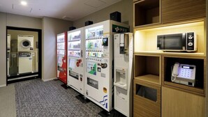 A hotel room with vending machines, a microwave, and a phone on a shelf. - JR Inn Sapporo N2 (Sapporo)