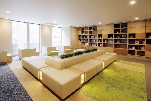 Une bibliothèque moderne avec un long canapé, des étagères et un sol recouvert de moquette.