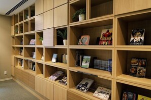 A library with wooden shelves containing books, magazines, and decorative items. - JR Inn Sapporo N2 (Sapporo)