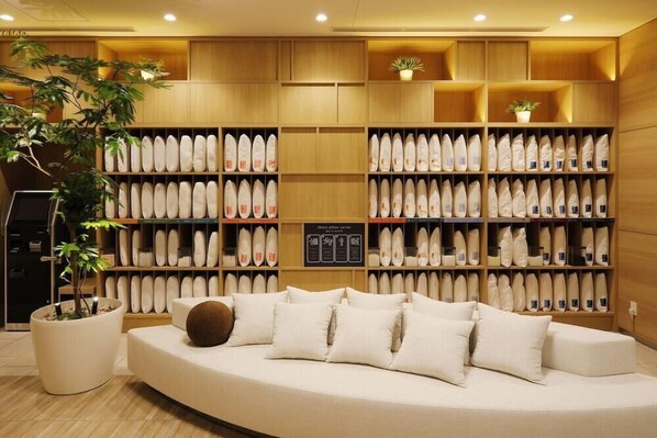 A modern interior with a sofa and shelves of shoes. - JR Inn Sapporo N2 (Sapporo)