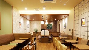 A restaurant with wooden tables and benches, a brick wall, and framed pictures on the walls. - JR Inn Sapporo N2 (Sapporo)