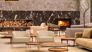 A modern living room with a fireplace, sofas, and a wood log display. - Laghetto Viverone Canela (Canela)