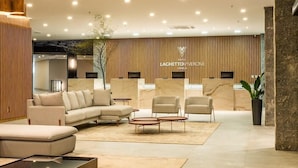 A modern reception area with a sofa, armchairs, and a reception desk. - Laghetto Viverone Canela (Canela)