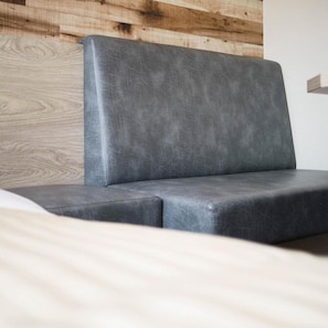 A modern, minimalist sofa with a textured fabric against a wooden wall. - Super Hotel Kushiro Natural Hot Springs (Kushiro)