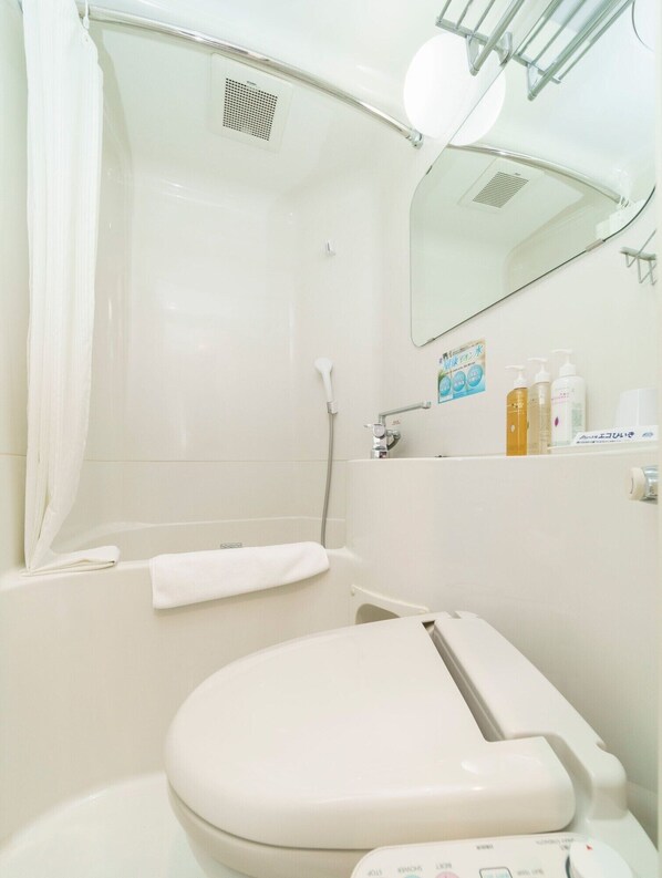 Une salle de bain moderne équipée d’une douche, de toilettes et d’un miroir.