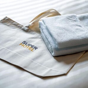 A folded towel and a white tote bag with 'SUPER HOTEL' text. - Super Hotel Okayama (Okayama)