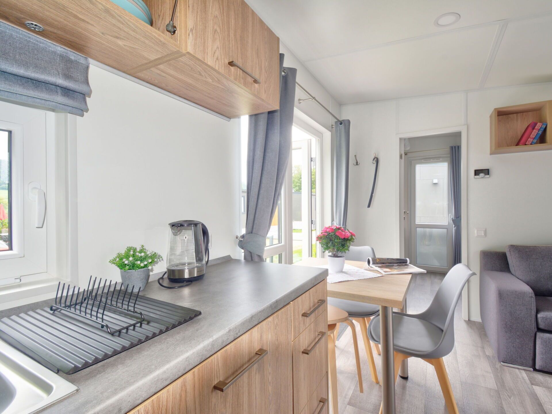 A compact kitchen with a sink, kettle, and a dining area with a table and chairs.