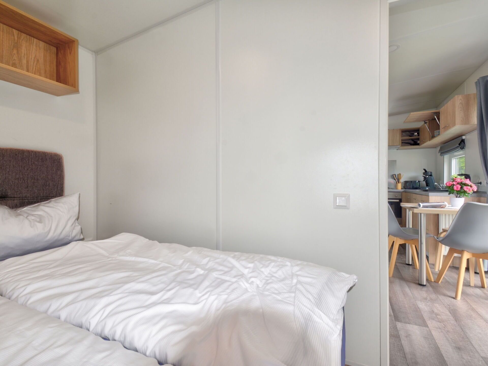 Een compacte, moderne kamer met een bed, een klein keukenhoekje en een eethoek.