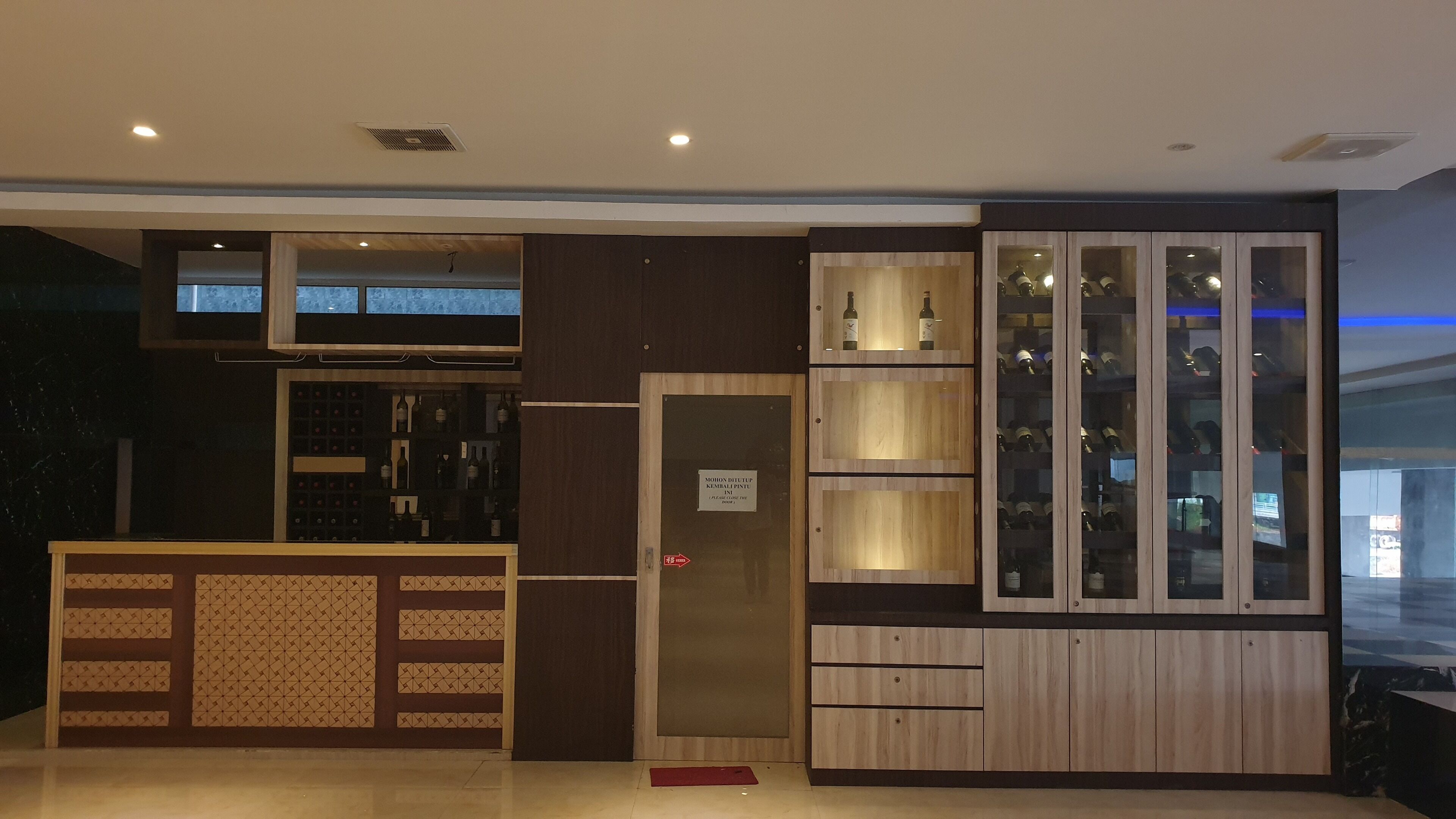 A bar area with wooden cabinets and shelves displaying bottles.