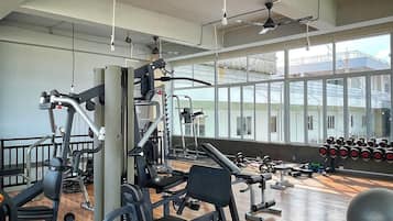 Una palestra con diverse attrezzature per esercizi, ampie finestre e pavimento in legno.