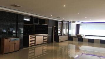Un'ampia hall d'albergo con pavimento lucido, una reception e un'ampia finestra che lascia entrare luce naturale.