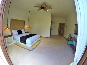 A bedroom with a bed, bedside tables, a ceiling fan, and a nightstand. - La Puerta Azul Beachfront - Adults Only (Isla Holbox)