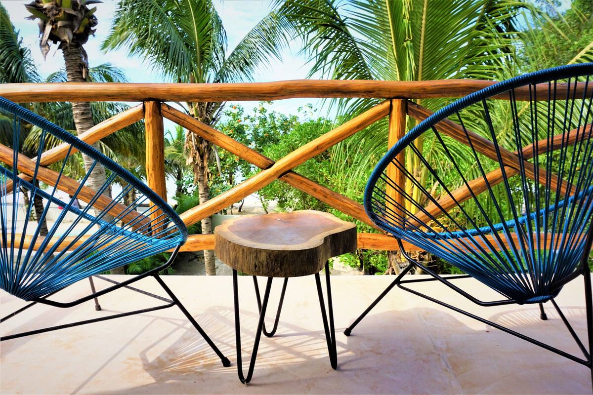 A wooden deck with two blue wire chairs and a small wooden table.