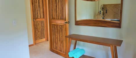 Un pasillo con puertas de madera, una consola de madera con una toalla y un espejo en la pared.
