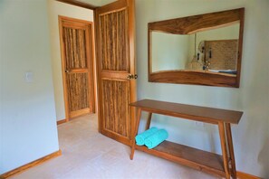 A hallway with wooden doors, a wooden console table with a towel, and a mirror on the wall. - La Puerta Azul Beachfront - Adults Only (Isla Holbox)