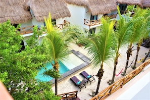 A poolside area with lounge chairs, a small pool, and thatched-roof structures. - La Puerta Azul Beachfront - Adults Only (Isla Holbox)
