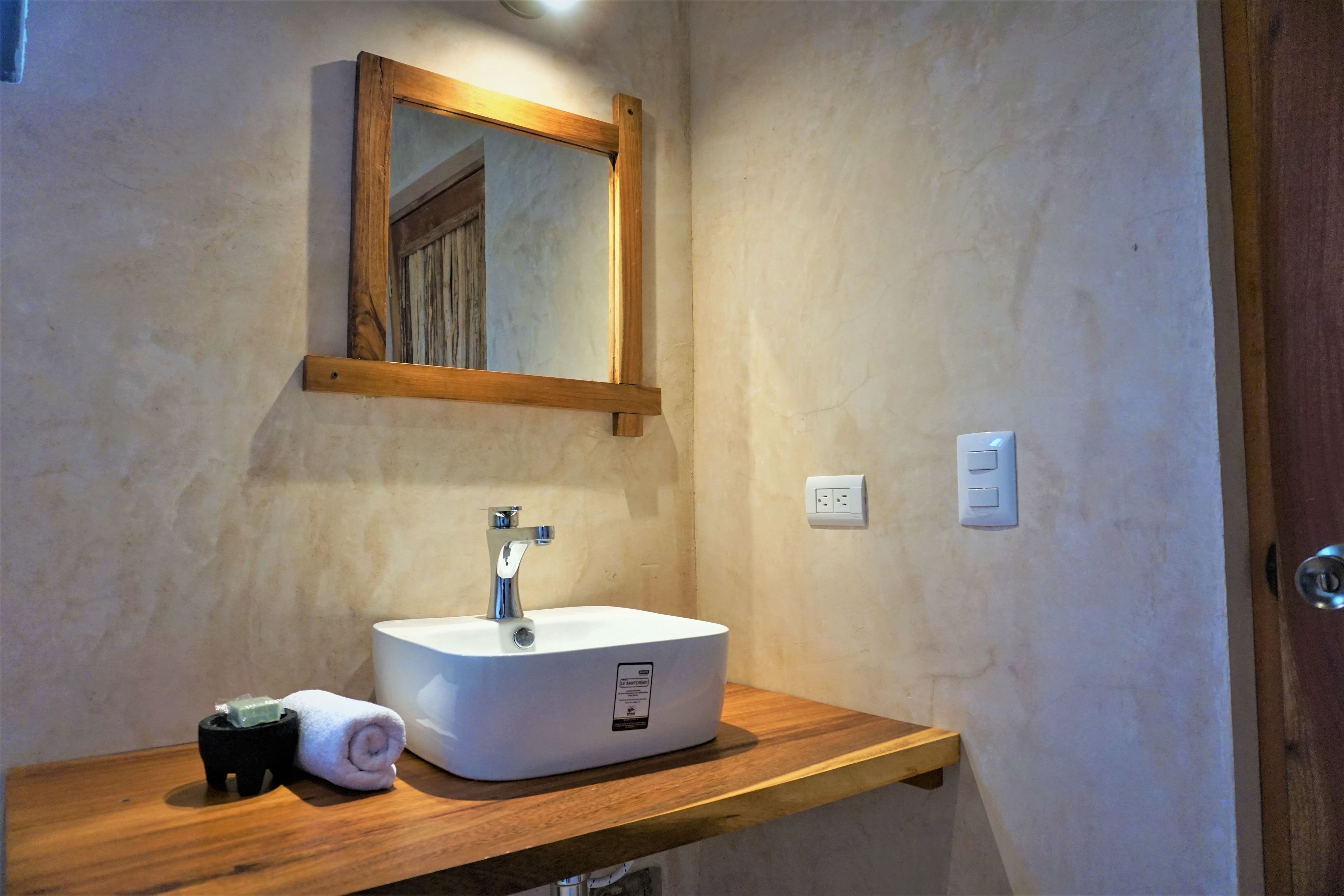 A bathroom with a wooden vanity, a white sink, a mirror, and a towel.