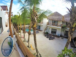 A resort with a pool, palm trees, and thatched-roof buildings. - La Puerta Azul Beachfront - Adults Only (Isla Holbox)