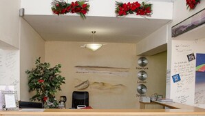 A reception desk with a clock, a coffee machine, and a wall with handwritten notes and a framed picture. - Seashells Holiday Self Catering Apartments (Jeffreys Bay)