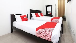 Een hotelkamer met twee bedden, elk met witte beddengoed en rode accenten, een donker houten hoofdeinde, een grote spiegel en een modern plafondontwerp.