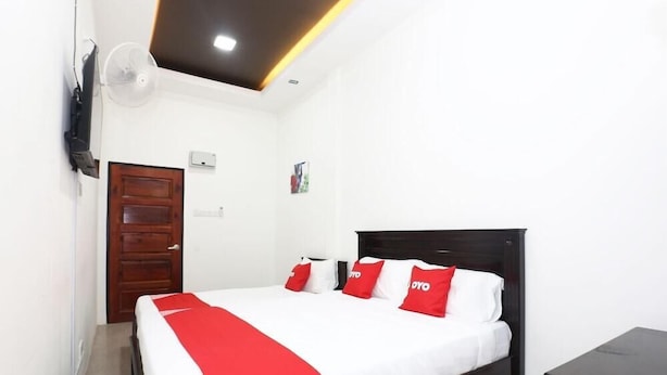 Een hotelkamer met een bed, een houten deur, een tv aan de muur en een plafondlamp.