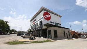 Een gebouw met een opvallend 'OYO'-bord, een winkelgevel en een parkeerplaats met meerdere voertuigen.