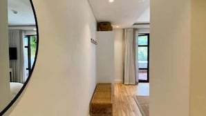 A narrow hallway with wooden flooring, white walls, and a large mirror on the left. - Barrington's (Plettenberg Bay)