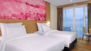A hotel room with two beds, a large pink artwork on the wall, and a view of the sea through the windows. - Favehotel Nagoya (Batam)