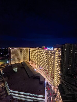 Un hôtel doté d’une grande façade illuminée et d’un espace aménagé sur le toit.