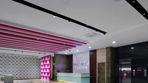 A hotel reception area with a modern design, including a reception desk, seating area, and a patterned wall. - Favehotel Nagoya (Batam)