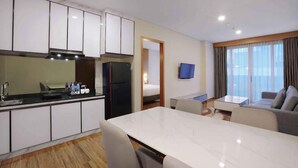 A modern hotel room with a kitchen, dining area, and a living space with a sofa and a TV. - Favehotel Nagoya (Batam)