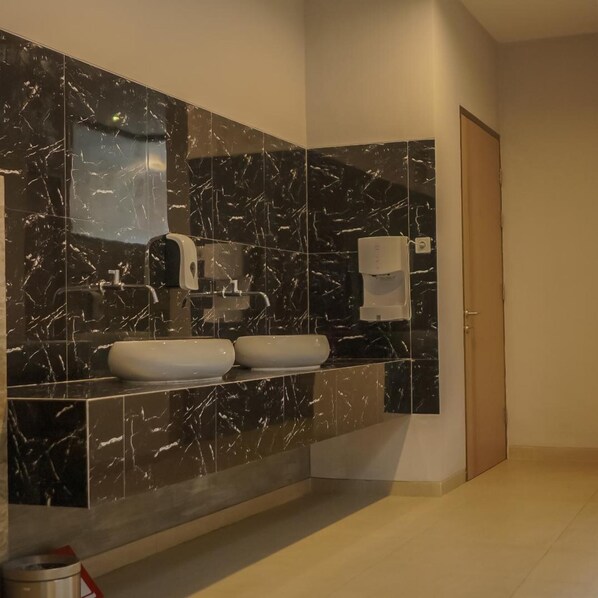 A modern bathroom with a large mirror, two sinks, and a toilet.