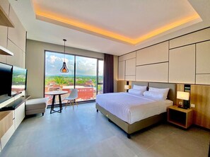 Una habitación de hotel moderna con una cama grande, televisión, escritorio y silla.
