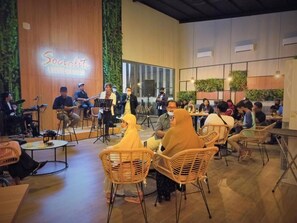 Un événement mondain avec un groupe jouant sur scène, des invités assis et une pancarte indiquant « Salon des personnalités ».