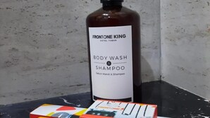A bottle of Frontone King body wash and shampoo, a shower cap, and a toothbrush on a black surface. - Front One King Hotel Tuban (Tuban)
