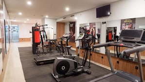 A modern gym with various cardio and strength training equipment, including treadmills, elliptical machines, and weight machines.