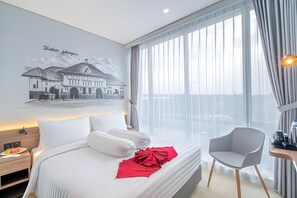 A hotel room with a bed, a chair, a desk, and a large window. - Azana Style Hotel Bandara (Tangerang)