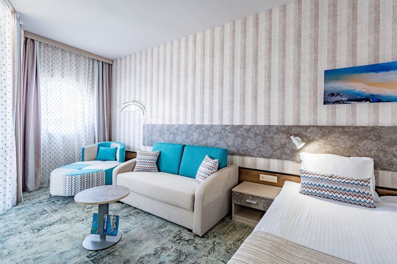 Una habitación de hotel con sofá, una mesita, cama y mesita de noche.