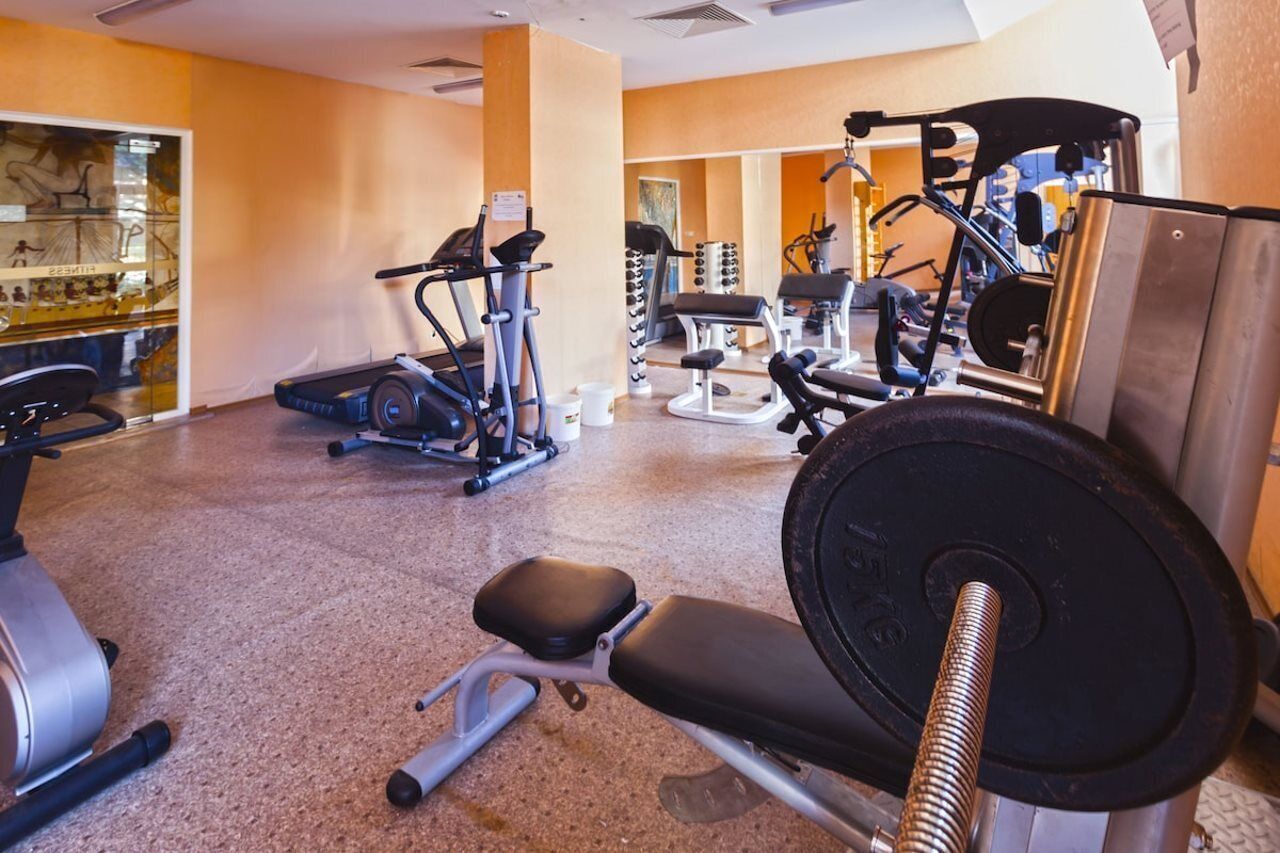 A gym with various exercise equipment including treadmills, weight machines, and free weights.