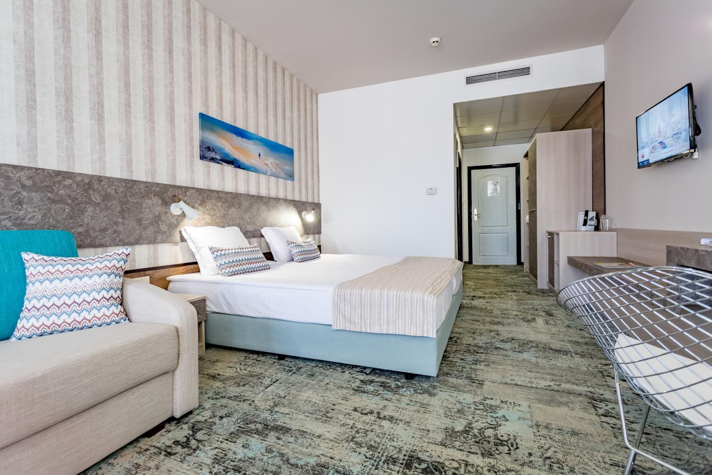 A hotel room with a bed, a sofa, a TV, and a desk.