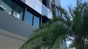 A multi-story building with a modern architectural design, featuring a mix of glass and metal elements, and a visible balcony on the upper floors. - The Chess Hotel (Rayong)