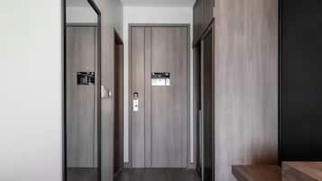 A hallway with two doors, one with a visible lock and a small sign, and a wooden bench to the right.