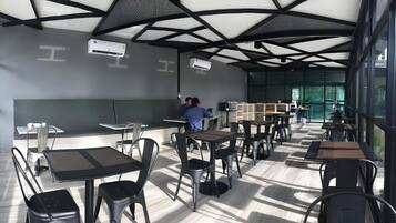 Un comedor moderno con mesas, sillas, ventiladores de techo y unidades de aire acondicionado.