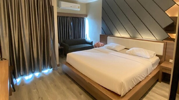 A modern hotel room with a large bed, a built-in desk, and a wall-mounted air conditioning unit. - The Chess Hotel (Rayong)