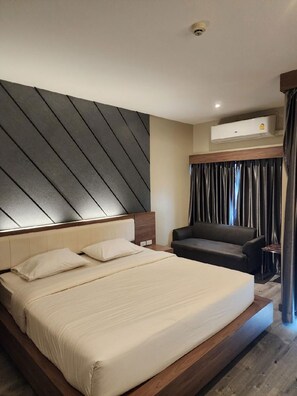 A modern hotel room with a large bed, a sofa, an air conditioning unit, and a view of the outside. - The Chess Hotel (Rayong)