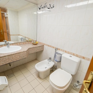 A bathroom with a sink, bidet, toilet, and a mirror. - Kindi Suites Hotel (Amman)