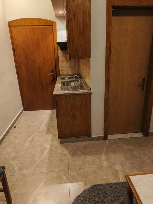 Una cocina compacta con lavamanos, armarios de madera y salpicadero de azulejos.