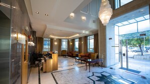 A spacious lobby with a marble floor, modern furniture, and large windows offering views of the outside. - Kindi Suites Hotel (Amman)