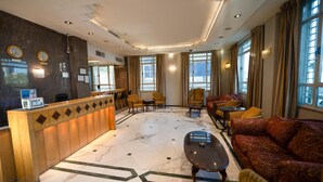 A lobby with a reception desk, seating area, and large windows. - Kindi Suites Hotel (Amman)