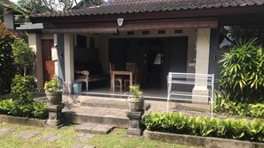 A traditional house with a tiled roof, a porch with a wooden bench, and potted plants. - Bali Breeze Bungalows (Ubud)